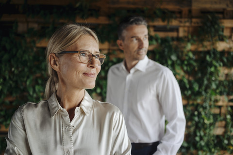 Businessman and businesswoman in green office thinking stock photo