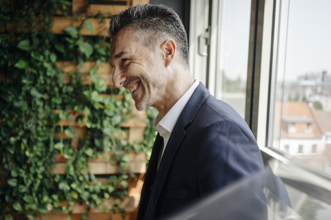 Happy businessman at the window in green office stock photo