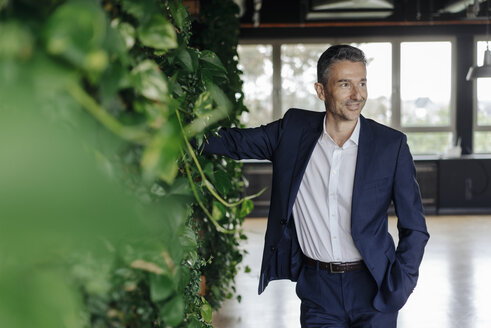 Smiling businessman in green office - JOSF01372