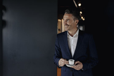 Lächelnder Geschäftsmann mit Espressotasse, der zur Seite blickt - JOSF01385