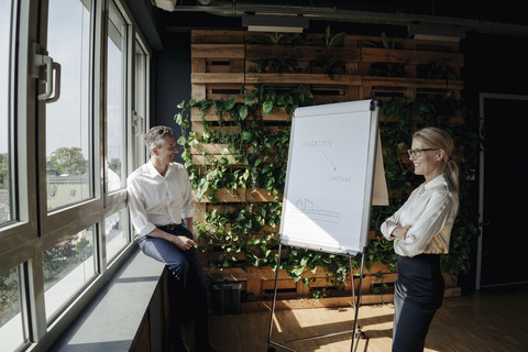 Geschäftsmann und Geschäftsfrau arbeiten mit Flipchart in grünem Büro, lizenzfreies Stockfoto