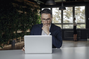 Geschäftsmann mit Laptop im grünen Büro - JOSF01403