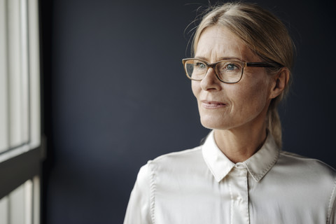 Businesswoman in office looking out of window stock photo