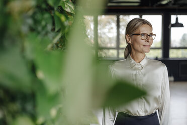 Smiling businesswoman in green office - JOSF01415