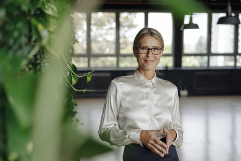 Porträt einer selbstbewussten Geschäftsfrau in einem grünen Büro, lizenzfreies Stockfoto