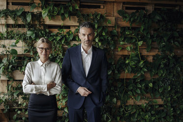 Portrait of confident businessman and businesswoman in green office - JOSF01424