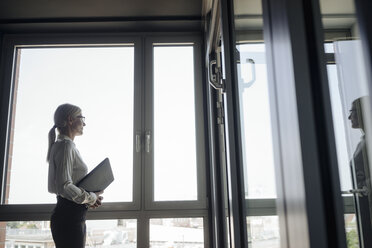 Businesswoman in office looking out of window - JOSF01430