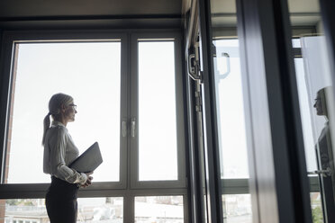 Geschäftsfrau im Büro schaut aus dem Fenster - JOSF01430