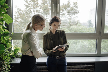 Zwei Geschäftsfrauen mit Tablet im Büro am Fenster - JOSF01443