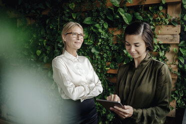 Two businesswomen with tablet in green office - JOSF01445