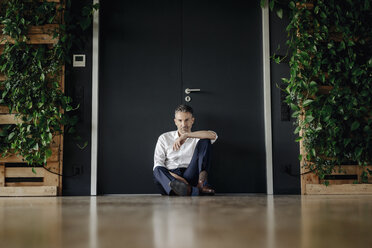 Businessman sitting on the floor in green office - JOSF01456