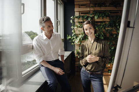 Geschäftsmann und Geschäftsfrau arbeiten mit Flipchart in grünem Büro, lizenzfreies Stockfoto