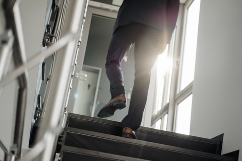 Beine eines Geschäftsmannes, der die Treppe hinaufgeht, lizenzfreies Stockfoto