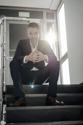 Portrait of confident businessman sitting on stairs - JOSF01497