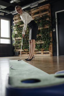 Businesswoman playing golf in office - JOSF01513