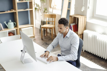 Geschäftsmann mit Computer am Schreibtisch im Büro - KNSF02440