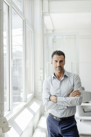 Porträt eines selbstbewussten Geschäftsmannes am Fenster, lizenzfreies Stockfoto