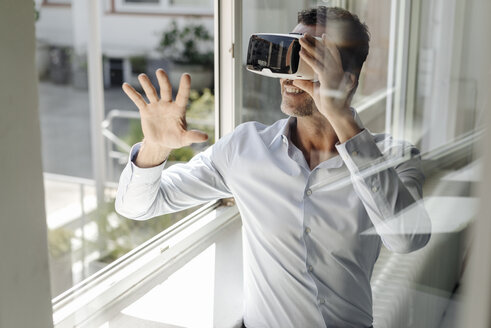 Geschäftsmann am Fenster mit VR-Brille - KNSF02463