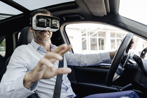 Businessman wearing VR glasses driving a car - KNSF02471