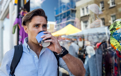 UK, London, Portobello Road, Porträt eines Mannes, der vor einem Schaufenster Kaffee trinkt - MGOF03586