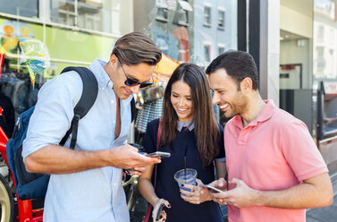 UK, London, Portobello Road, drei lächelnde Freunde schauen auf ihr Handy - MGOF03588