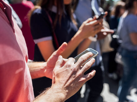 Männerhand mit Smartphone auf der Straße - MGOF03596