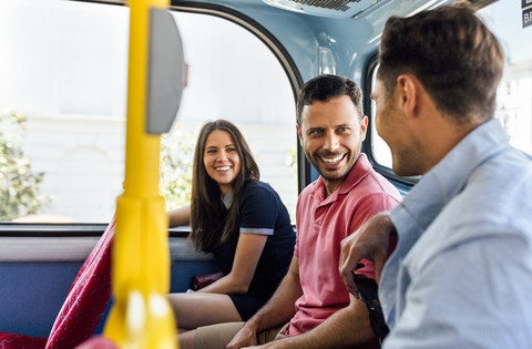 Großbritannien, London, drei Freunde sitzen in einem Doppeldeckerbus und unterhalten sich, lizenzfreies Stockfoto