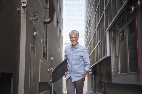 Mature man with longboard in an alley stock photo