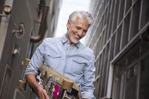 Mature man with longboard in an alley - WESTF23560