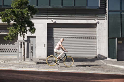 Älterer Mann fährt Fahrrad in der Stadt, lizenzfreies Stockfoto