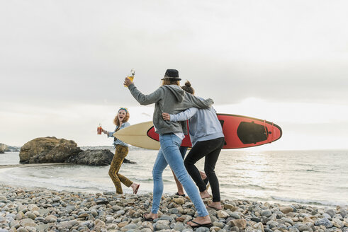 Glückliche Freunde mit Surfbrettern am steinigen Strand - UUF11638