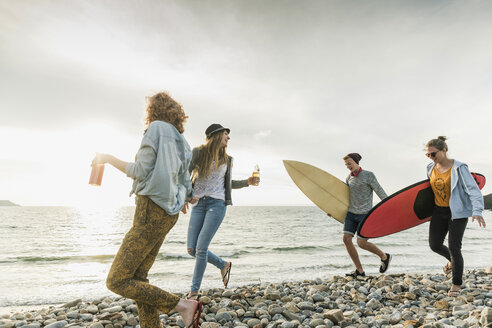 Glückliche Freunde mit Surfbrettern am steinigen Strand - UUF11642