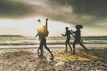 Excited friends on the beach at sunset - UUF11646