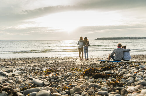 Freunde mit Surfbrett beobachten den Sonnenuntergang am Strand - UUF11658