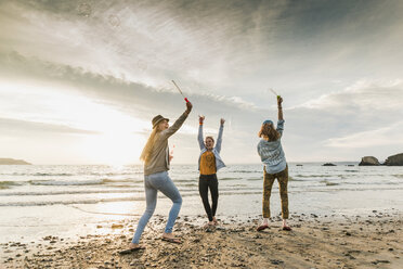 Happy friends making soap bubbles on the beach - UUF11665