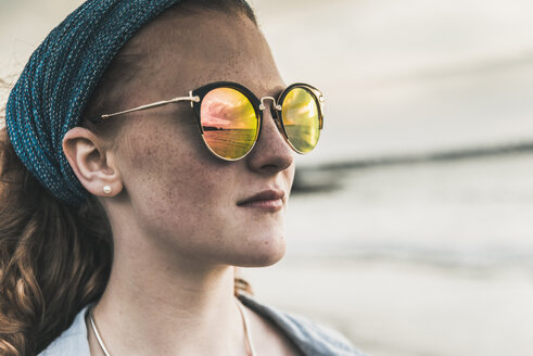 Reflection of clouds in sunglasses of young woman at sunset on the beach - UUF11669