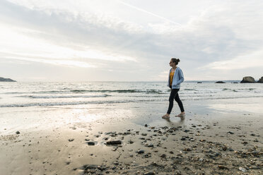 Junge Frau beobachtet den Sonnenuntergang am Strand - UUF11672