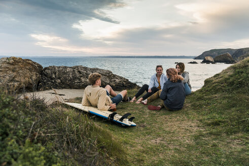 Glückliche Freunde mit Surfbrett, die sich bei Sonnenuntergang an der Küste treffen - UUF11674