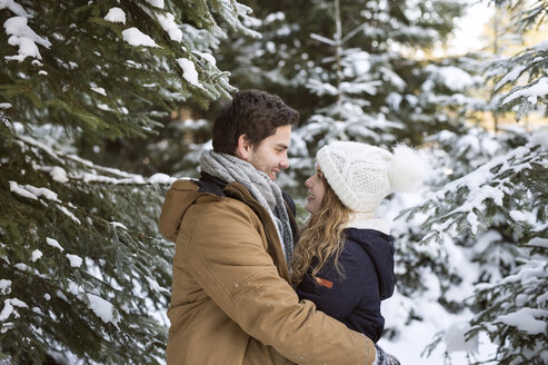 Glückliches junges Paar von Angesicht zu Angesicht im schneebedeckten Winterwald - HAPF02022