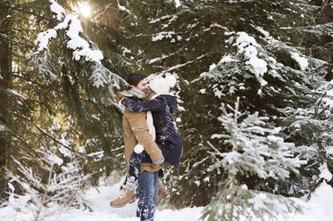 Glückliches junges Paar von Angesicht zu Angesicht im schneebedeckten Winterwald - HAPF02024