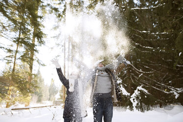 Glückliches junges Paar wirft im Wald Schnee in die Luft - HAPF02028