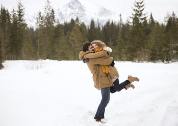 Glückliches junges Paar in schneebedeckter Winterlandschaft - HAPF02037