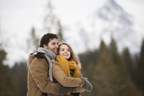 Porträt eines glücklichen jungen Paares in einer Winterlandschaft, lizenzfreies Stockfoto