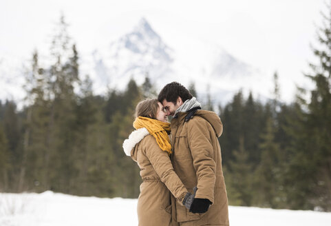 Glückliches junges Paar steht Kopf an Kopf in einer Winterlandschaft - HAPF02042