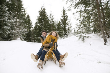 Happy young couple on sledge in winter forest - HAPF02043