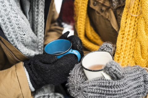 Young couple wearing gloves holding cups of tea in winter, close-up stock photo