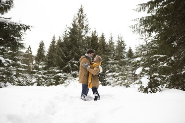Glückliches junges Paar, das in einer Winterlandschaft von Angesicht zu Angesicht steht - HAPF02054