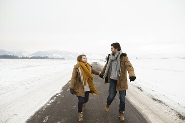 Junges verliebtes Paar auf leerer Landstraße in schneebedeckter Landschaft - HAPF02057