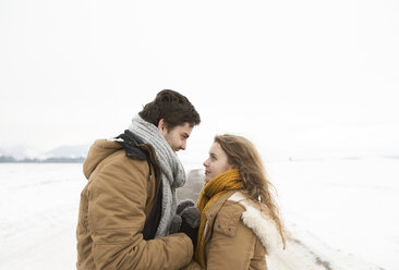 Young couple in love standing face to face on country road in snow-covered landscape - HAPF02058