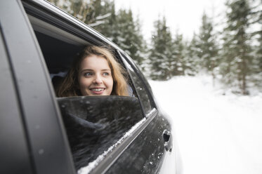 Young woman looking out of a car window in winter landscape - HAPF02066